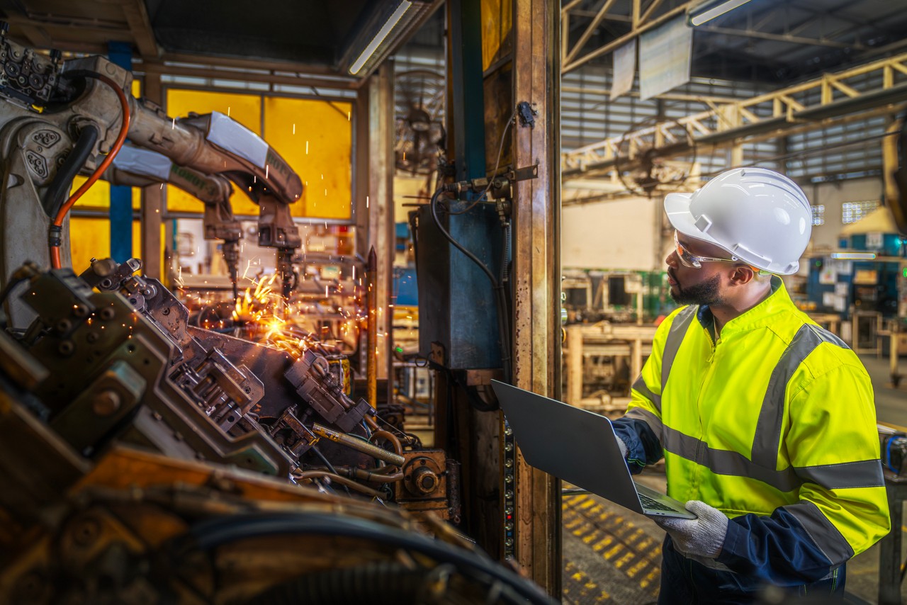 African american worker working in old united state factory in robot auto welding machine section and welding for assembly matal part, America