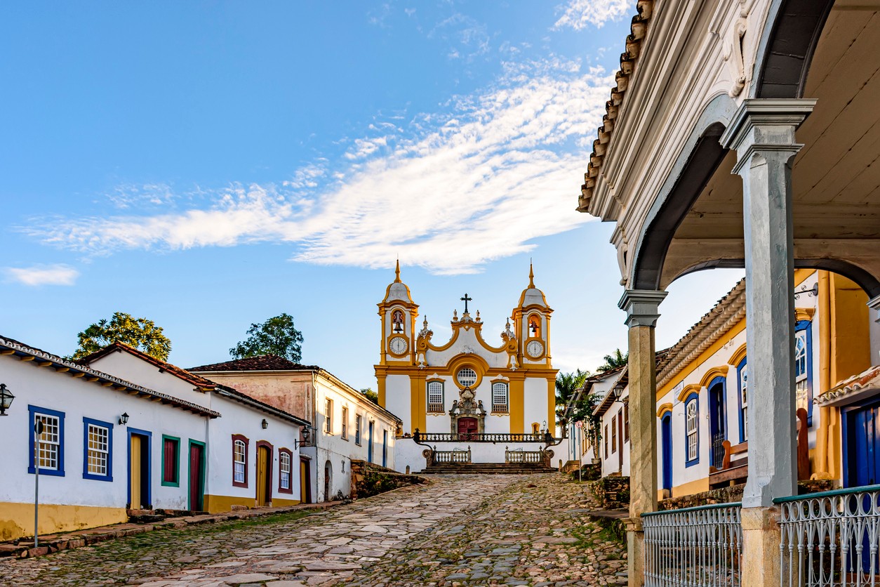 A quiet historic street in the city of Tiradentes in Minas Gerais with colonial houses and a baroque church in the background