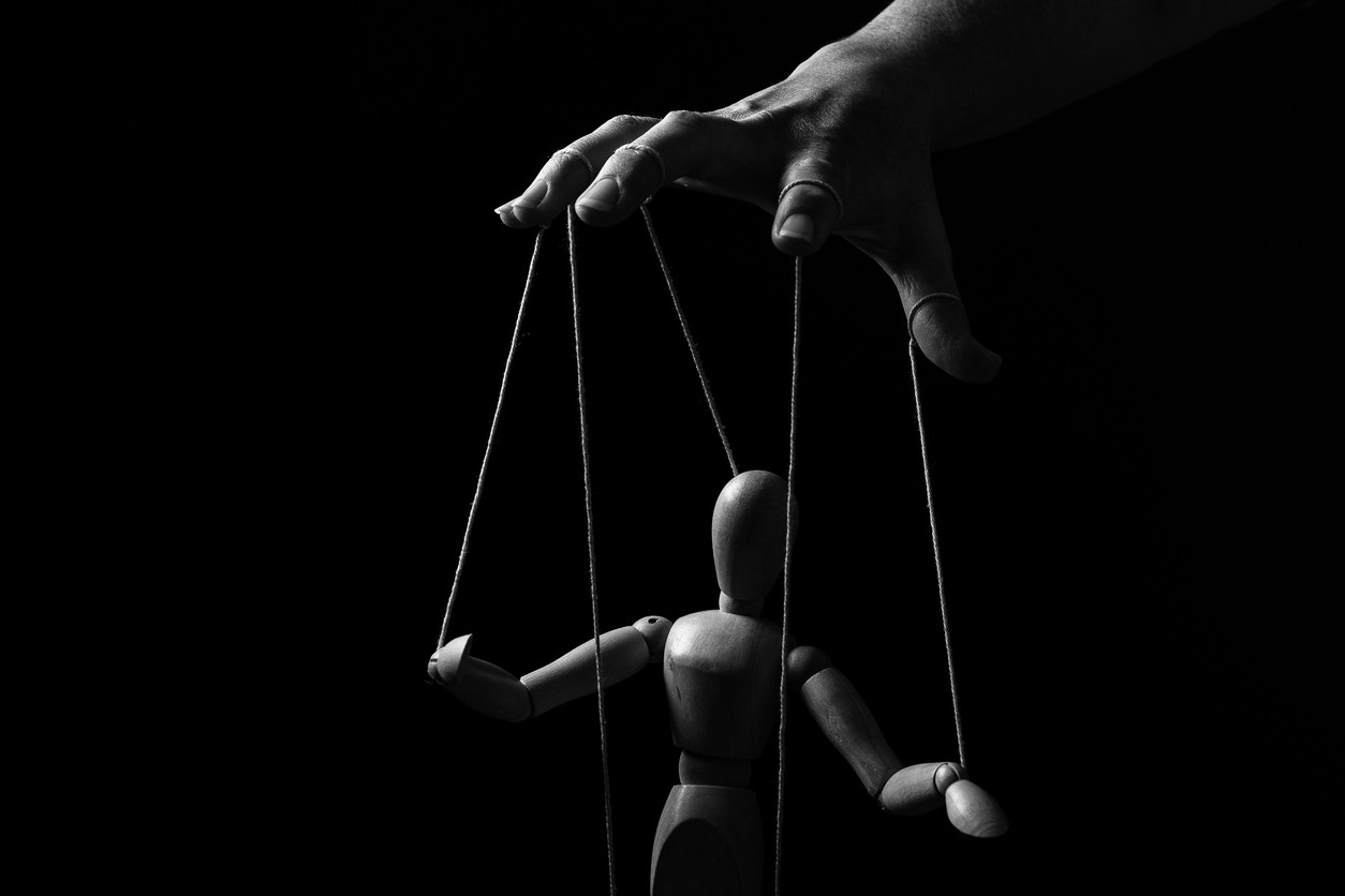 Conceptual image of a hand with strings on fingers to control a marionette in monochrome