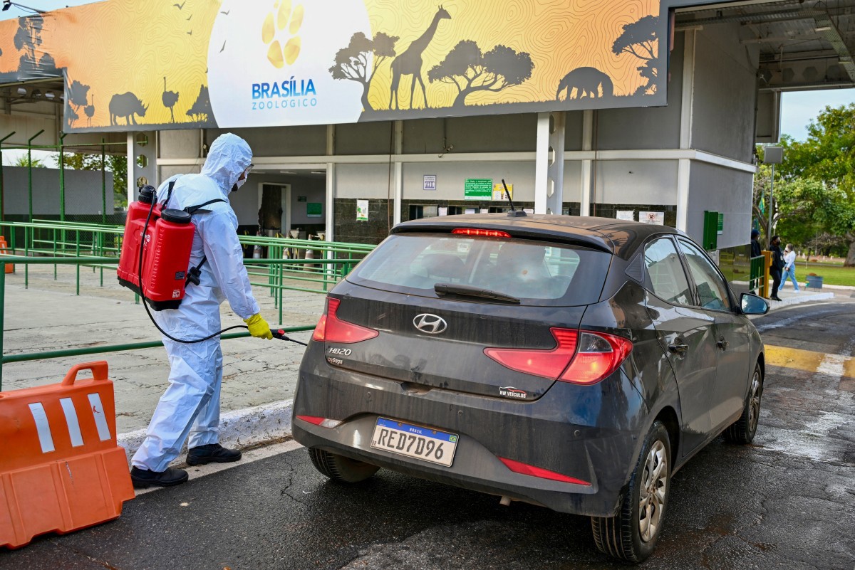Funcionário do Zoológico de Brasília desinfeta carro de um funcionário do parque, em meio a suspeita de gripe aviária  