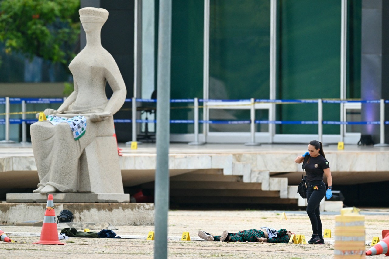 Perita da Polícia Federal trabalha na Praça dos Três Poderes, onde o corpo permanecia exposto até a manhã desta quinta-feira (14)