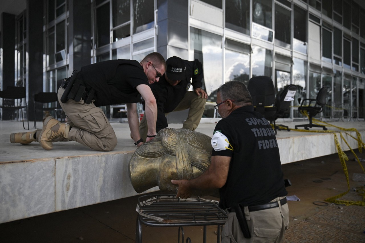 Integrante da força policial que atua no STF carregam estátua vandalizada por apoiadores de Jair Bolsonaro durante os atos de 8 de janeiro de 2023,  em que pediam prisão de ministros da Corte e intervenção militar