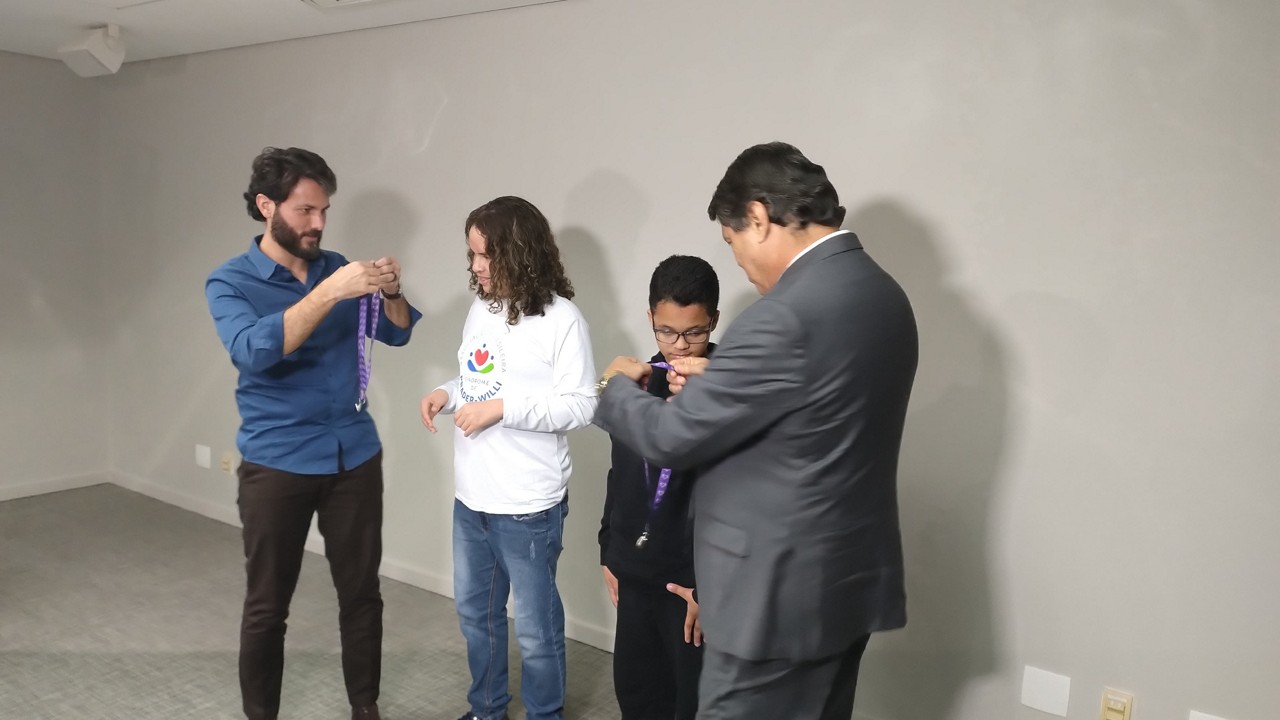 Secretário de Governo, Marcelo Aro (PP), realizou uma sanção simbólica com a entrega de cordões a dois pacientes com doenças raras.
