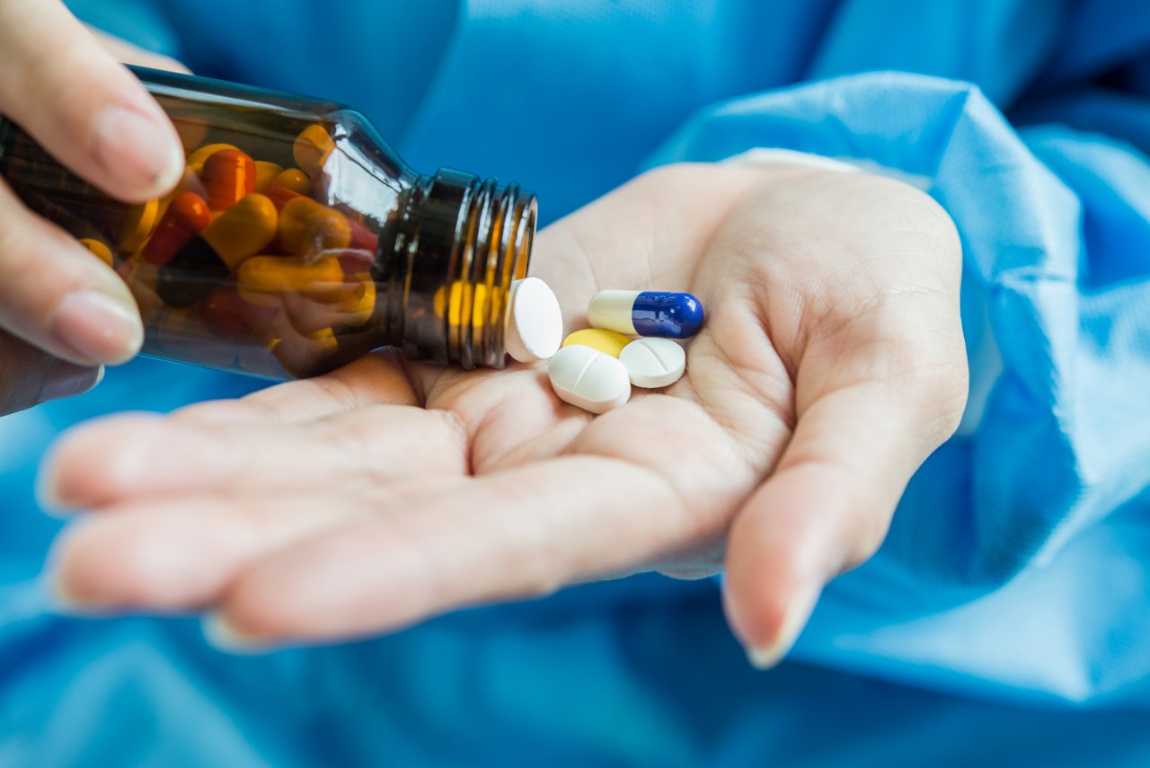 Woman's hand pours the medicine pills out of the bottle
