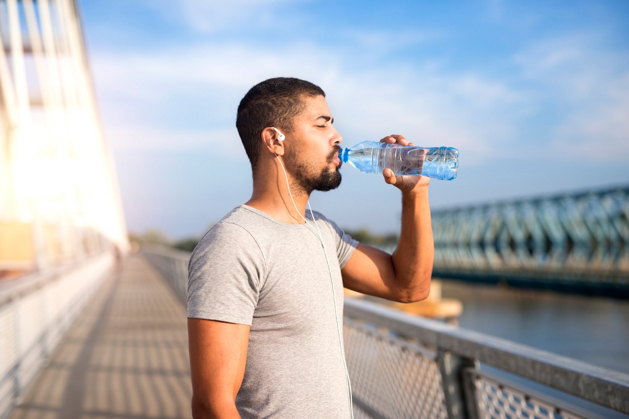 Attractive sportsman drinking water after hard training.