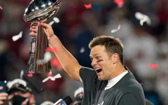 Tom Brady, maior vencedor de Super Bowls da NFL, segurando o trofeu Vince Lombardi