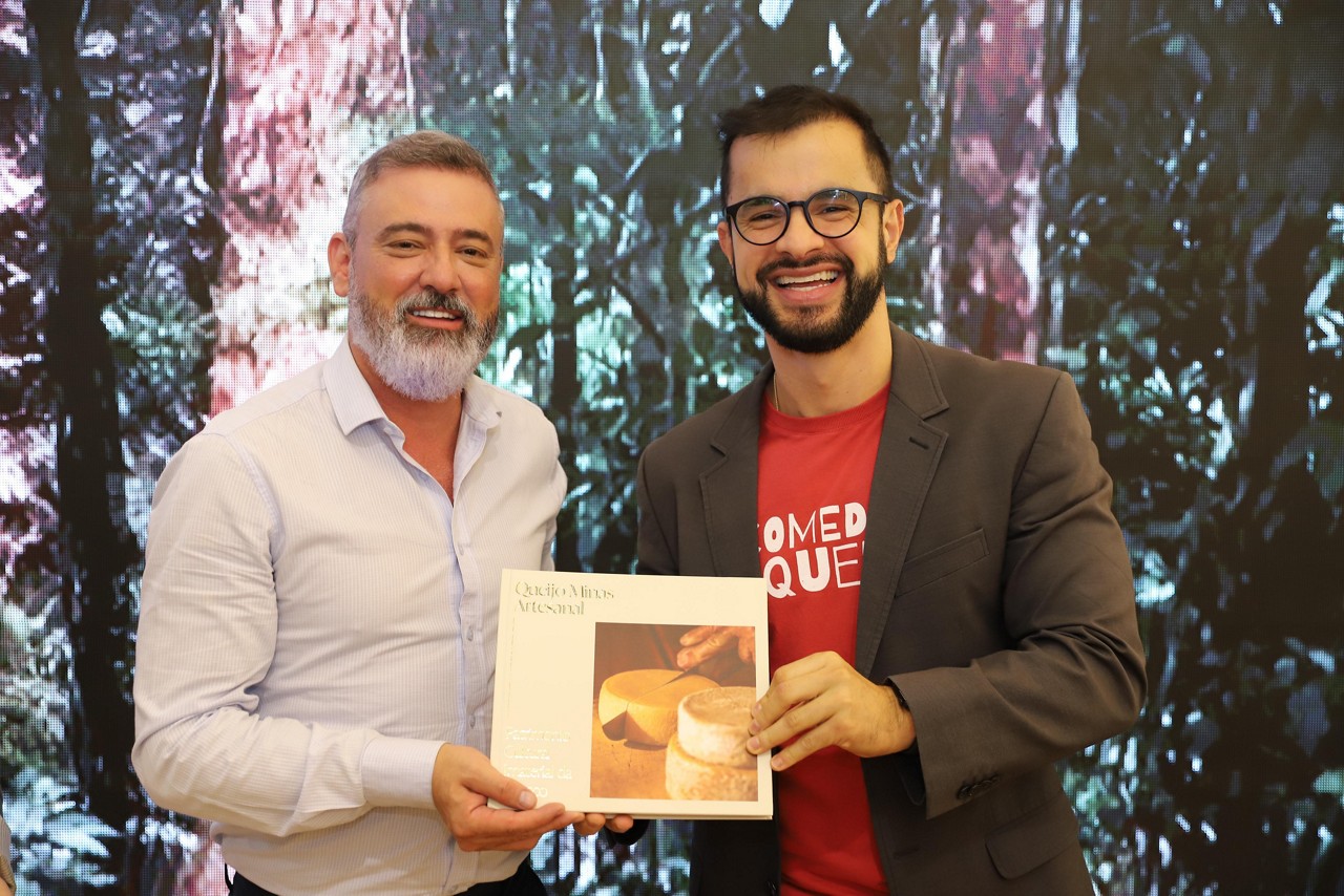 O secretário Leônidas Oliveira e o historiador Roger Vieira exibem o livro durante o lançamento no estande de Minas