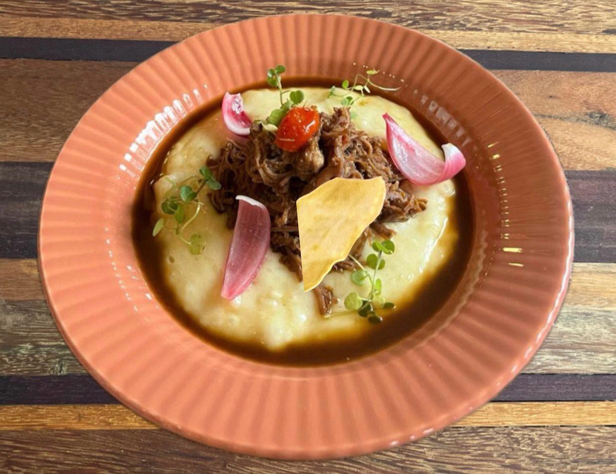 Sabor Inconfidente, do restaurante Sankofa Bistrô e Galeria: ragu de maçã de peito cozida na cerveja preta, acompanhado de mousseline de mandioca cremosa, picles de cebola roxa, tomate confit, broto de agrião e chips de mandioca crocante.